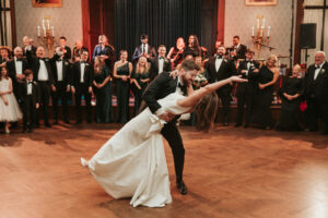 Groom dips his bride on the dance floor at the Philadelphia Union League as Jellyroll plays a song and guests look on. 